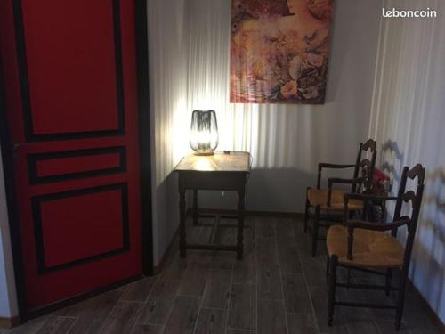 um quarto com uma mesa e cadeiras e uma porta vermelha em Granal em Saint-Julien-Gaulène