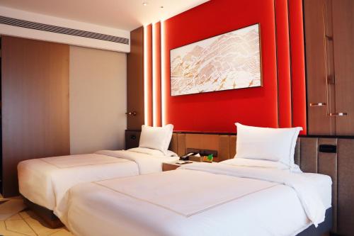 two beds in a room with a red wall at La Quinta by Wyndham Weifang South in Weifang