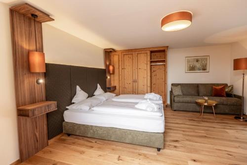 a bedroom with a bed and a couch at Moseralm Dolomiti Spa Resort in Nova Levante