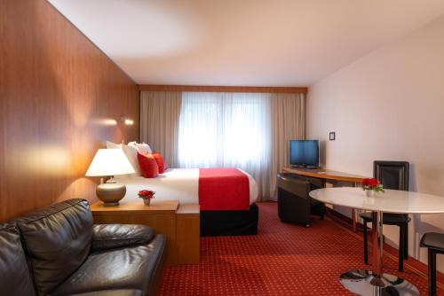 a hotel room with a bed and a desk at Le M & Spa Bordeaux Aéroport by Hôtels & Préférence in Mérignac