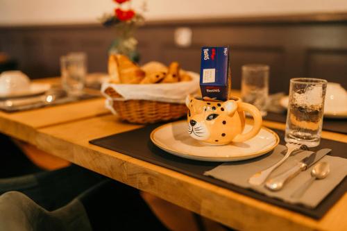 a table with a plate with a cat cup on it at Hôtel Le Cro-Magnon in Les Eyzies-de-Tayac