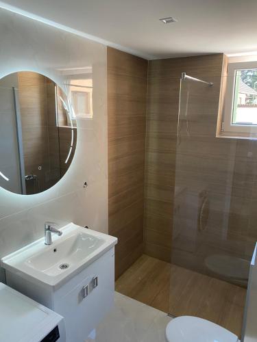 a bathroom with a sink and a shower with a mirror at Mia apartman Visoko in Visoko