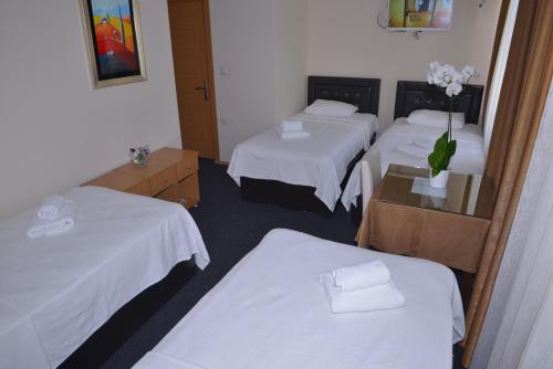 a hotel room with three beds with white sheets at Kervan Hotel Pendik in Istanbul