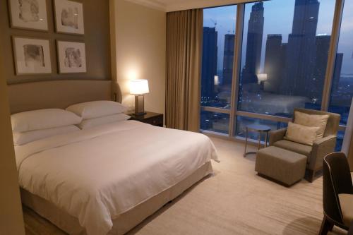 a hotel room with a bed and a chair and a window at Address fountain views apartments in Dubai
