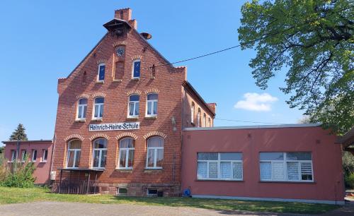 an old brick building with a clock on top of it at Gästehaus Heinrich Heine Schule in Bad Dürrenberg