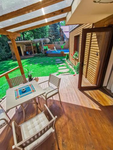 a patio with a table and chairs and a yard at Вила Край реката in Botevgrad