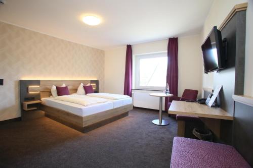 a bedroom with a bed and a desk with a computer at Hotel Münchner Hof in Herford