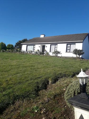 a white house with a green lawn in front of it at Room in Bungalow - Very Nice View With This Room in Sneem