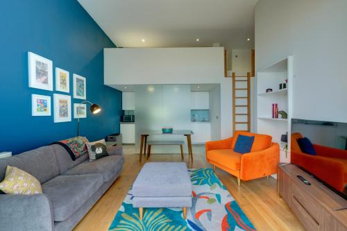 uma sala de estar com um sofá e uma cadeira laranja em 2 Bed- Pureserviced 5 Brewhouse em Plymouth