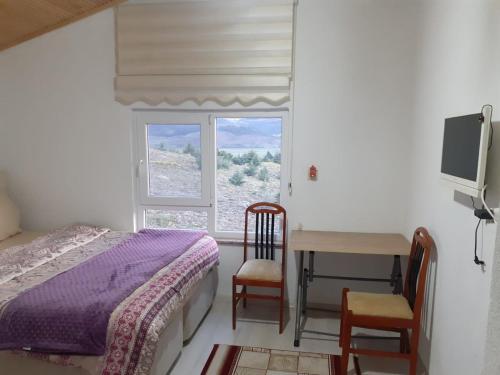 a bedroom with a bed and a desk and a window at Salda Gölü Çeliköz Apart in Yeşilova