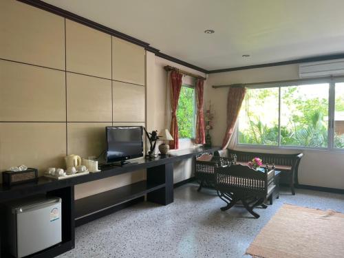 a living room with a television and a table and chairs at Lotus Paradise Resort - SHA PLUS in Ko Tao
