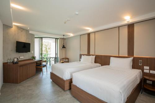a hotel room with two beds and a television at Dewa Phuket Resort & Villas, Nai Yang Beach in Nai Yang Beach