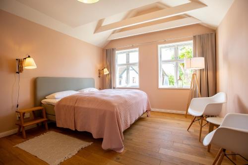 a bedroom with a bed and two chairs and a window at Kapitänshaus Luv & Lee in Wustrow