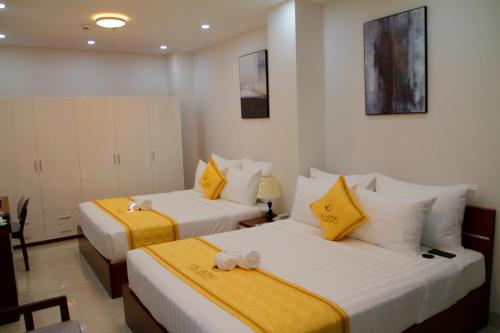 two beds in a room with yellow and white at Khách Sạn Lạc Hồng Mỹ Tho - Lac Hong My Tho Hotel in My Tho