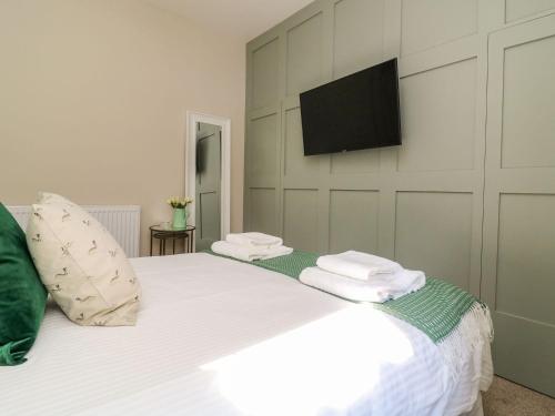 a bedroom with a white bed with a flat screen tv on the wall at Fonaby in Market Rasen