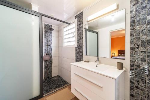 ein Badezimmer mit einem weißen Waschbecken und einer Dusche in der Unterkunft Kaz Noulafé in Saint-Leu