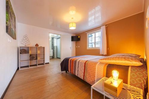 a bedroom with a bed and a table with a lamp at Kaz Noulafé in Saint-Leu