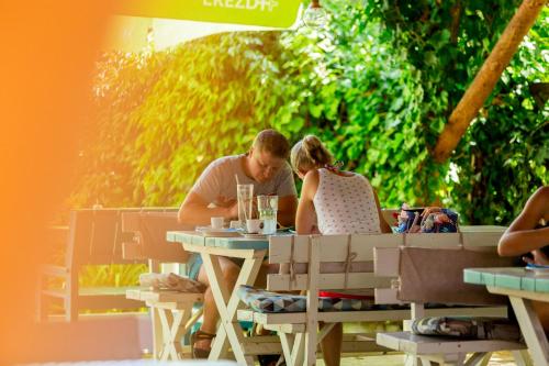 a man and woman sitting at an outdoor table at Fészek -Étel és Hotel- in Zánka