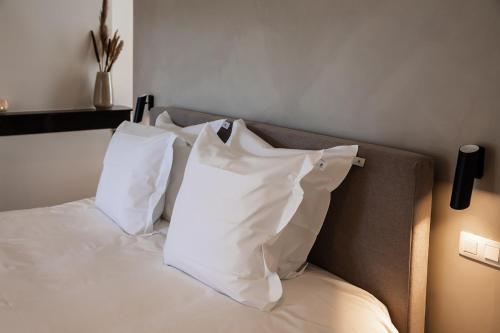 a bed with white pillows on top of it at Villa Ostinato in Ostend