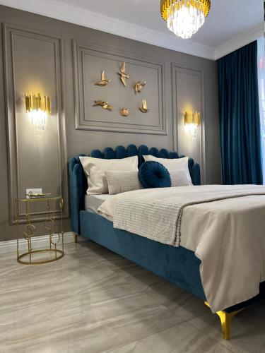 a bedroom with a blue bed with birds on the wall at Golden Apartment in Oradea