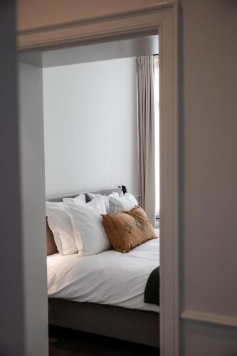 a bedroom with a bed with white pillows and a mirror at Villa Ostinato in Ostend