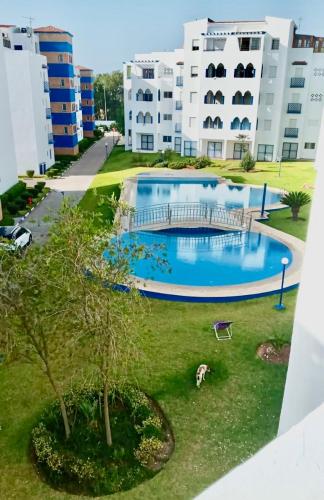 a large swimming pool in front of some buildings at TANGER/ASILAH: APPART 50m2 FACE MER ET PISCINES, 5 PLACES, TOUT ÉQUIPÉ+WIFI+CLIM in Briech