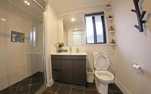 a bathroom with a toilet and a sink and a shower at Granny Flat next to golf course in Stanthorpe