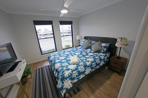 a bedroom with a bed and a tv and windows at Granny Flat next to golf course in Stanthorpe