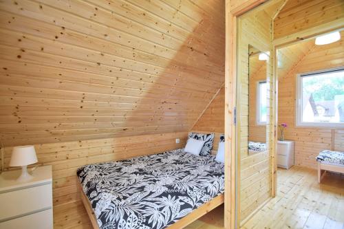 a log cabin with a bed in a room at Domki Biała Perła Gąski in Gąski