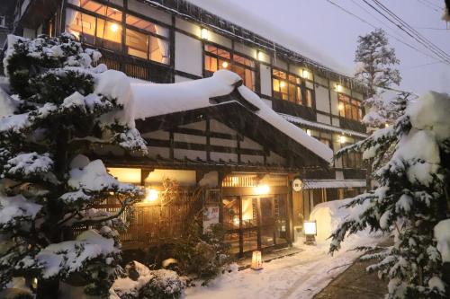 un edificio cubierto de nieve por la noche en 野沢温泉　奈良屋旅館, en Nozawa Onsen