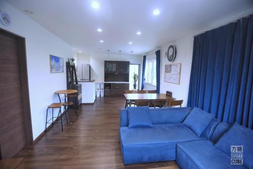 a living room with a blue couch and a kitchen at Furano CUBE SUGAR-方糖民宿,步行8min到雪场,3 brs,Max 6ppl in Furano
