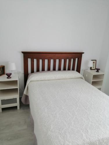 a bedroom with a white bed with a wooden headboard at Hormaza Chiclana in Chiclana de la Frontera