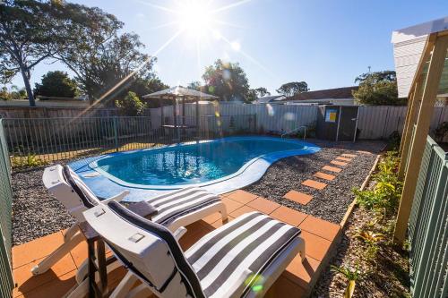 a swimming pool with two lounge chairs next to it at Flora Parade 6 in Tuncurry