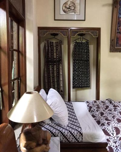 a bedroom with a bed with a lamp and a dresser at Nirvana Pension in Ubud
