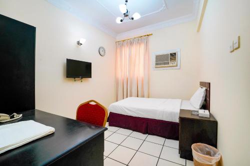 a hotel room with a bed and a desk and a tv at OYO 124 Al Salam Palace Hotel in Manama