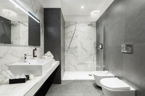 a white bathroom with a sink and a toilet at DA ME Suites in Rome