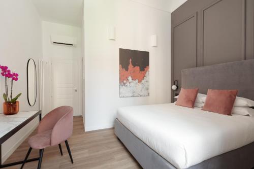 a bedroom with a white bed and a pink chair at DA ME Suites in Rome
