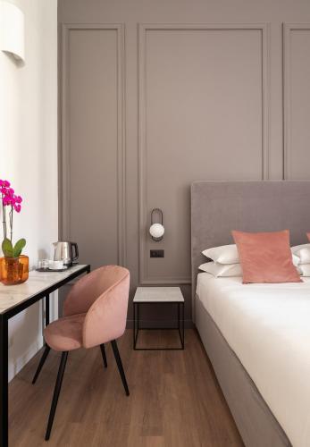 a bedroom with a bed and a desk and a chair at DA ME Suites in Rome