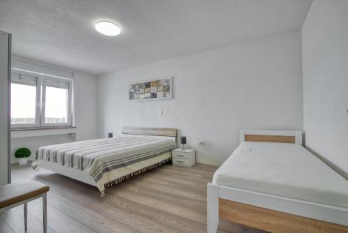 two beds in a room with white walls and wooden floors at Apartment Marina with sea view in Pula