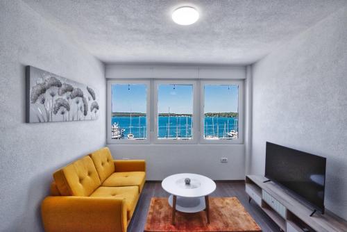 ein Wohnzimmer mit einem gelben Stuhl und einem TV in der Unterkunft Apartment Marina with sea view in Pula