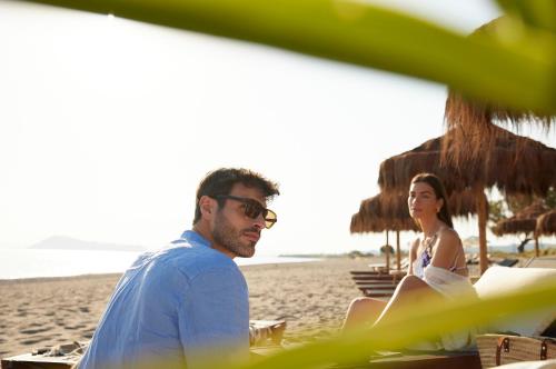 a man and a woman sitting on the beach at Asterion Suites & Spa - Designed for Adults in Gerani Chanion