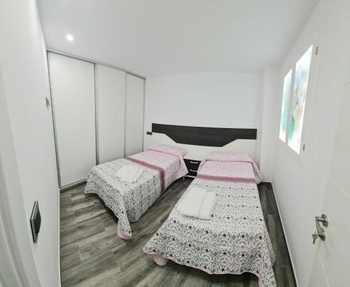 2 camas en una habitación pequeña con sábanas rosas en APARTAMENTOS DESAMPARADOS, en Murcia