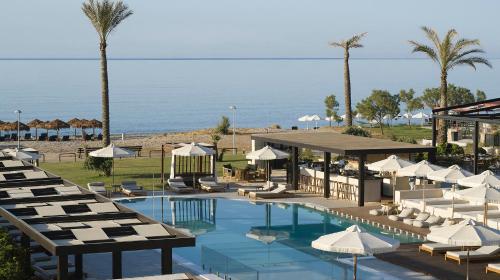 a pool with chairs and umbrellas next to the ocean at Asterion Suites & Spa - Designed for Adults in Gerani Chanion