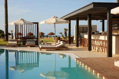 a swimming pool with chairs and umbrellas next to a house at Asterion Suites & Spa - Designed for Adults in Gerani Chanion