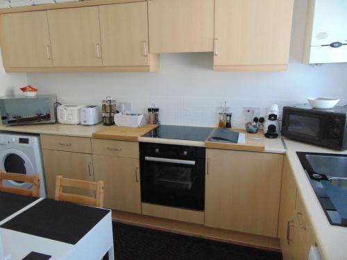 a kitchen with wooden cabinets and a stove top oven at Stony Apartment House in Doncaster