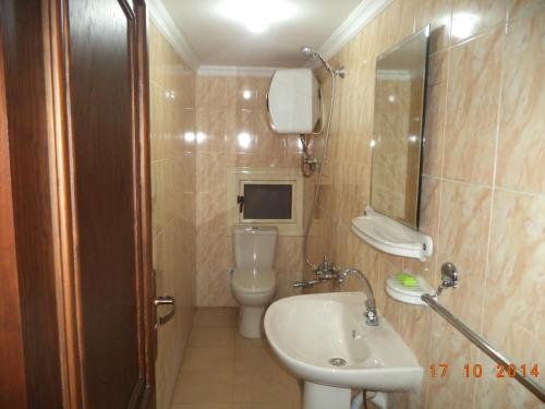 uma casa de banho com um lavatório, um WC e um espelho. em Al Maghraby Hotel em Alexandria