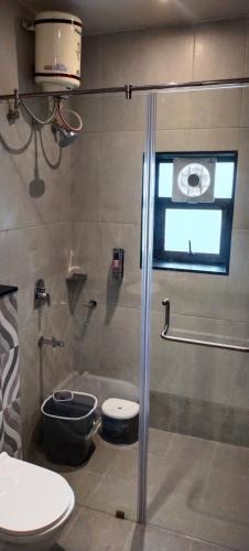 a bathroom with a shower with a toilet and a window at Kohinoor Exotica in Lonavala