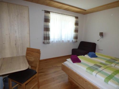a bedroom with a bed and a chair and a desk at Alpenchalet Breitspitz in Partenen