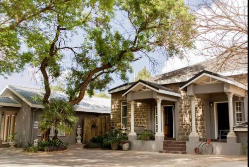 a stone house with a tree in front of it at Villa Twente Guest House in Lichtenburg