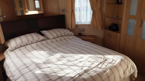 a large bed in a small room at 6 BERTH DELUXE ML7 ON THE GOLDEN PALM in Chapel Saint Leonards